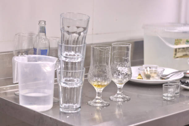 A bunch of dirty glasses and plates piled up in a restaurant kitchen