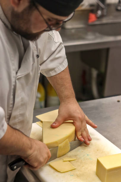 istock Chef cutting cheese on a board in the kitchen of a restaurant 2154739979