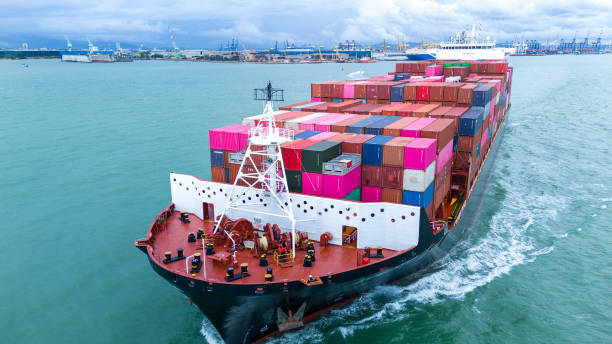 istock Side view of Cargo container ship carrying container and running out international container port customs shipyard sea port concept smart logistic service. 2154740536
