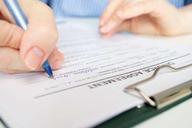 istock Divorce agreement, hand fills out a document, finalizing the breakup, legal paperwork, resolving marital conflict, court proceedings 2154741275