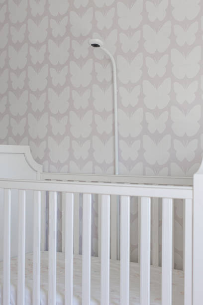 istock Cute Baby Crib in A Patterned Nursery with Security Camera 2154741546