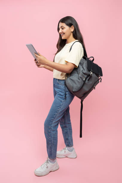istock Smiling young student girl with backpack and digital tablet 2154743379