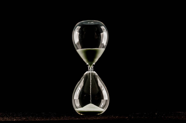 istock A glass hourglass with sand in it is shown on a black background 2154743873
