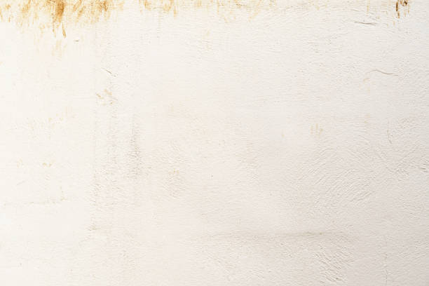 Dirty old uneven render concrete wall with red soil stains. Grunge and rough surface.