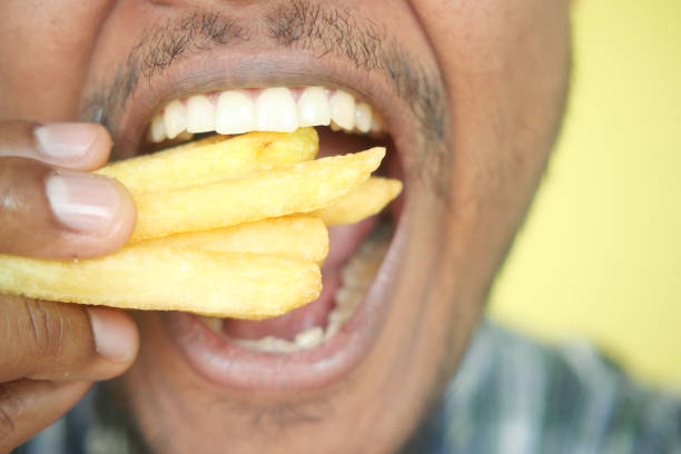 istock hungry man eating fries closeup 2154751296