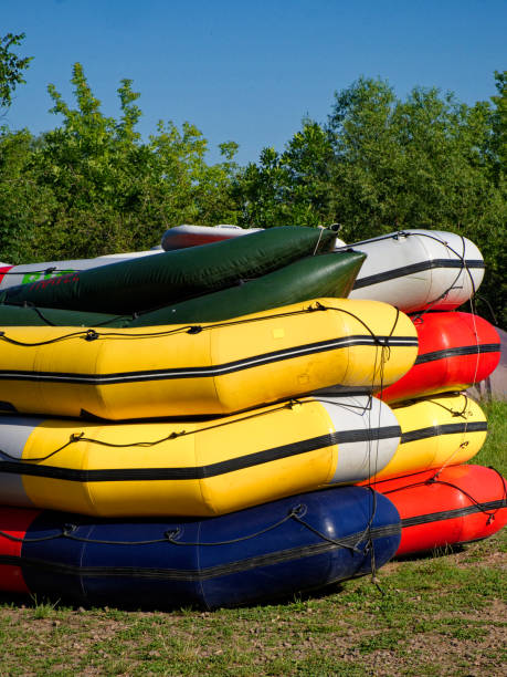 istock Brightly colored canoes stacked up, ready for use near a wooded area. 2154754631