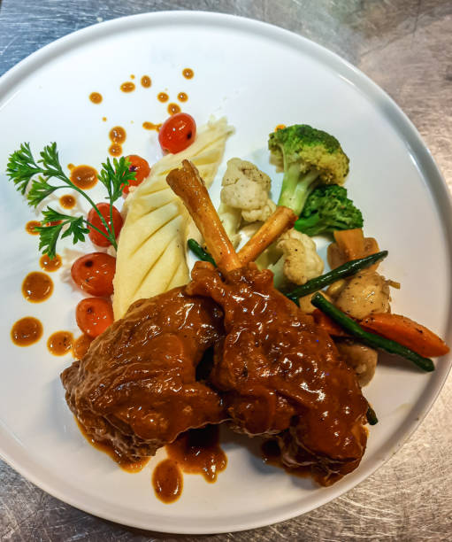 Braised lamb shank in restaurant. Modern style traditional braised slow cooked lamb shank in red wine sauce with shallots and mashed potatoes offered as top view with copy space.