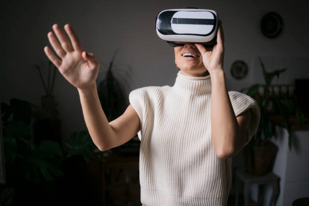 istock Young woman experiencing virtual reality with vr glasses at home 2154756534