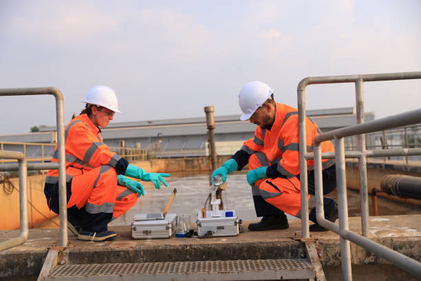 istock Safety and environmental engineers examining the water sample from the wastewater pond on a sunny day 2154756729