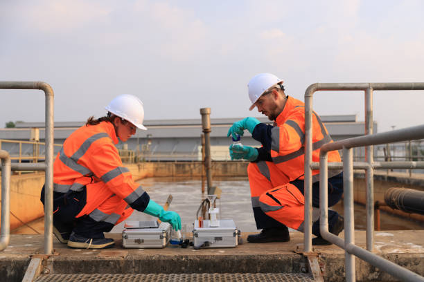 istock Safety and environmental engineers examining the water sample from the wastewater pond on a sunny day 2154756734