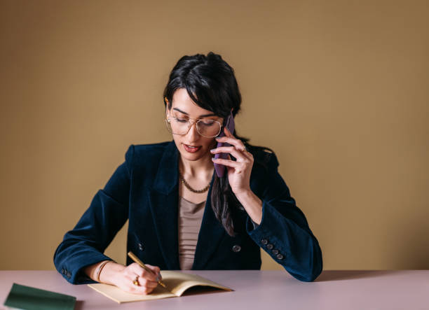 istock Professional Woman on Phone Taking Notes in Office 2154762916