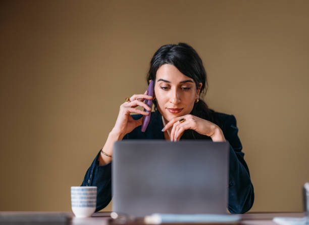 istock Professional Woman Working on Laptop and Talking on Phone 2154762932