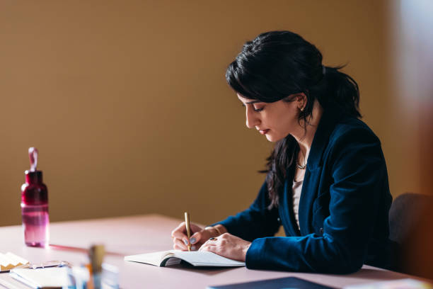 istock Focused Businesswoman Writing Notes at Desk in Office 2154762962