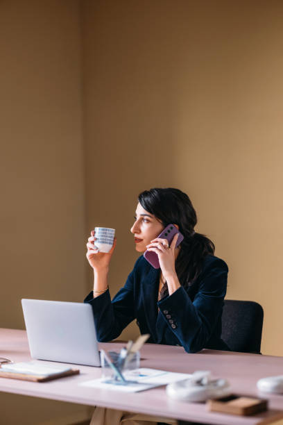 Businesswoman Multitasking with Coffee and Phone in Office