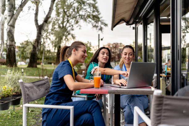 istock Nurses engage in group laptop session in cafe garden 2154764494
