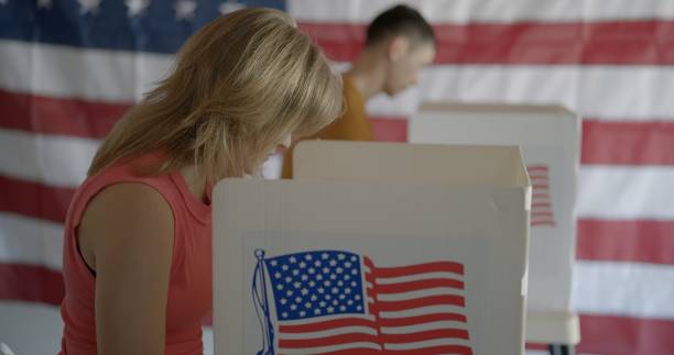 istock MS young woman voting and considering choices, US flag behind 2154771610