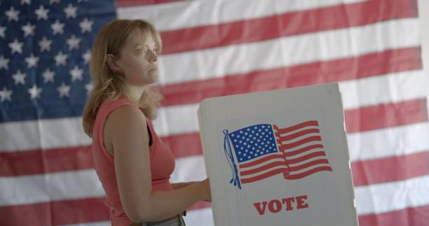 istock Angled MS young woman looks to side, considering election, US flag behind 2154771641