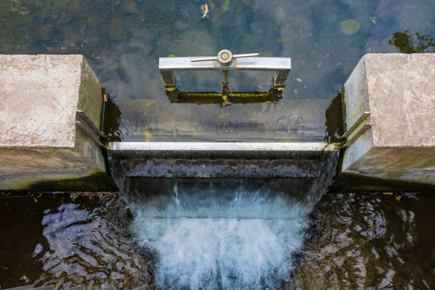 istock Small overflow dam sluice on a small river. Gateway with a waterfall to control the water level 2154771742