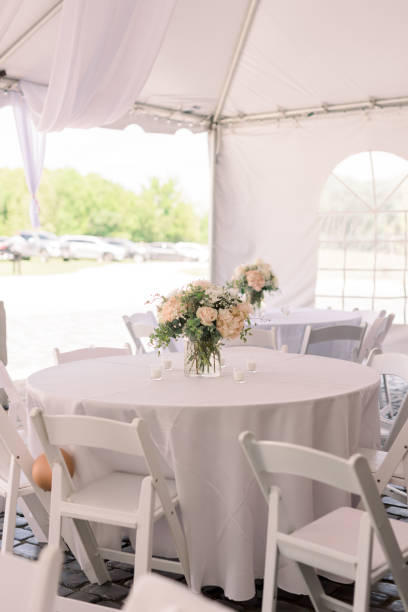 istock A simple white table with tablecloth and white chairs at a tented wedding reception. 2154772987