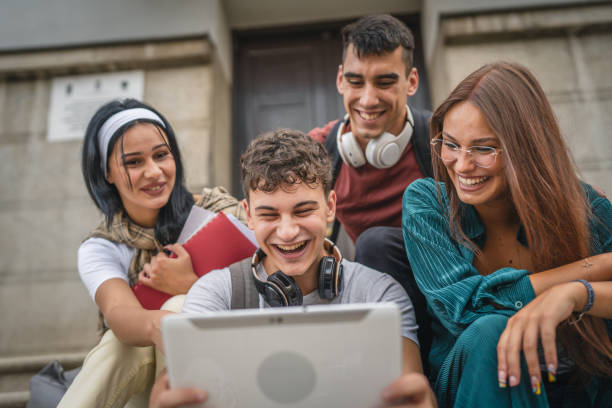 istock group of students sit in front of school watch video on digital tablet 2154774521
