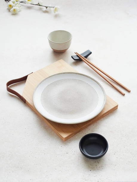 istock Simple and minimalist composition of tableware for oriental food on table, black and white plate and bowls, bamboo board and chopsticks. 2154774745