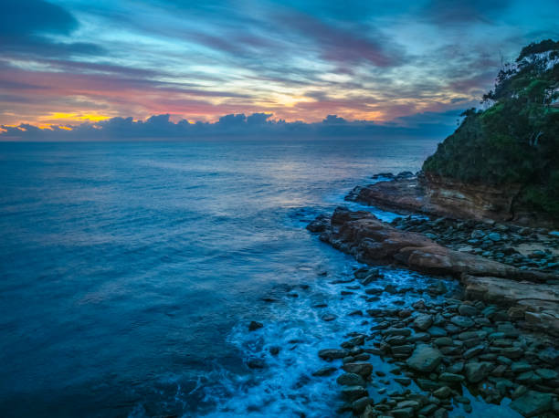 The interplay of fog and high clouds adds an enchanting touch to this coastal sunrise scene at Avoca Beach on the Central Coast of New South Wales, Australia.