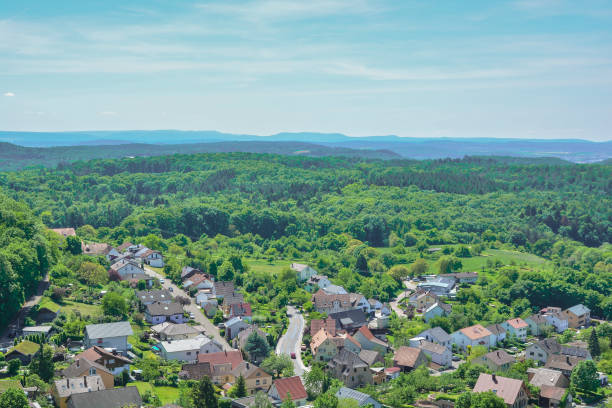 istock Aerial view of a small town surrounded by trees under a sunny sky 2154779889