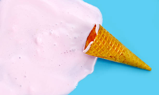 istock Melting ice cream ball with waffle cone on blue background. 2154787090