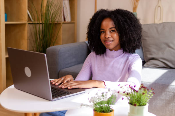 istock Smiling woman working on laptop at home 2154789502