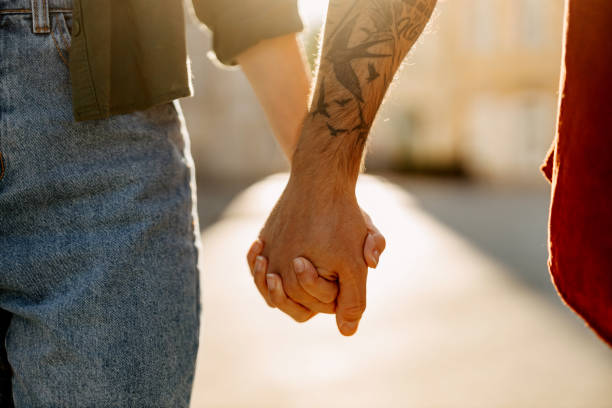 Close-up view of a loving couple's interlocked hands, showcasing intimate details like the tattoo and reflecting bonds of love and comfort