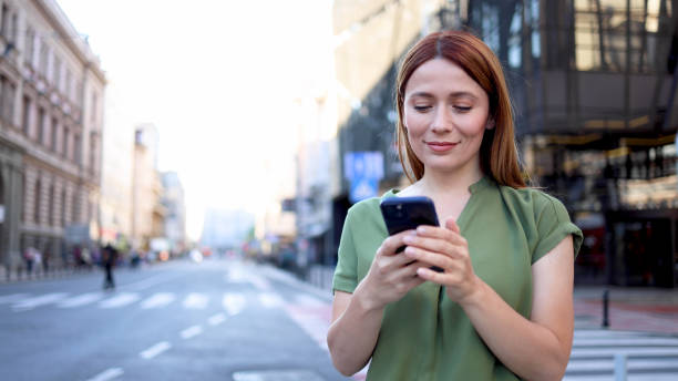 istock Beautiful, young woman walking through the city and using smartphone 2154792198