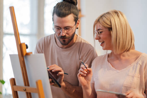 istock Precise creative couple at atelier painting together on easel. 2154795471