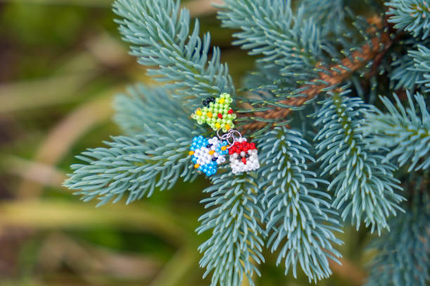 Christmas beaded charms on a blue spruce branch: Santa, tree, and penguin.