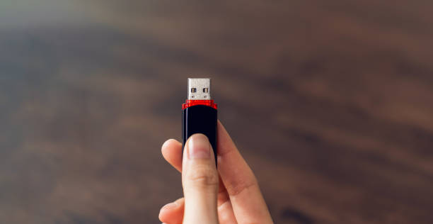 istock Hand holding usb flash drive with connecting to laptop at wooden table 2154806311