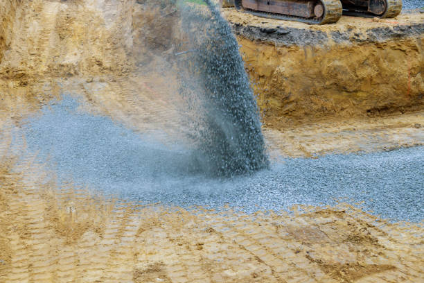 An excavator fills irregularities in excavations with granite rubble base so that concrete foundation can be laid