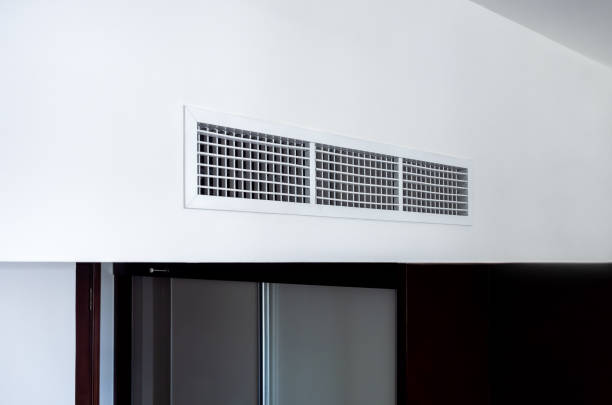 Side view of air conditioning wall mounted ventilation system on ceiling in the black and white hotel room. Hotel room air ventilation grill on the wall.