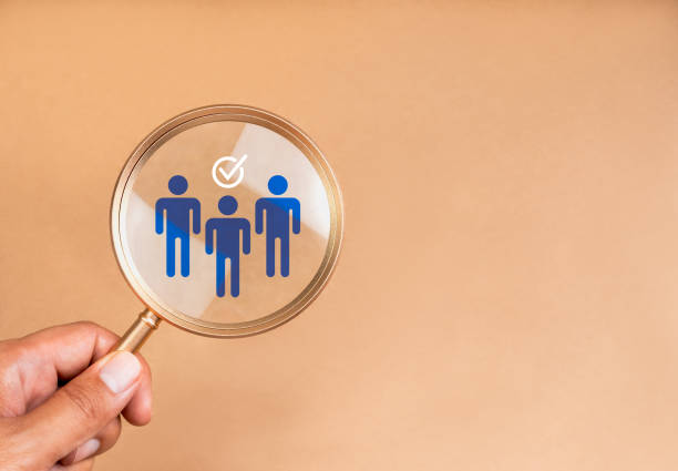 istock Human resource (HR), team hiring, teamwork recruitment concept. Working personnel group symbol with checkmark icon in magnifying glass lens holding by hand, on bright beige background with copy space. 2154807237