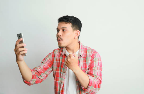 istock Asian man holding mobile phone and feeling shocked portrait white isolated 2154809382