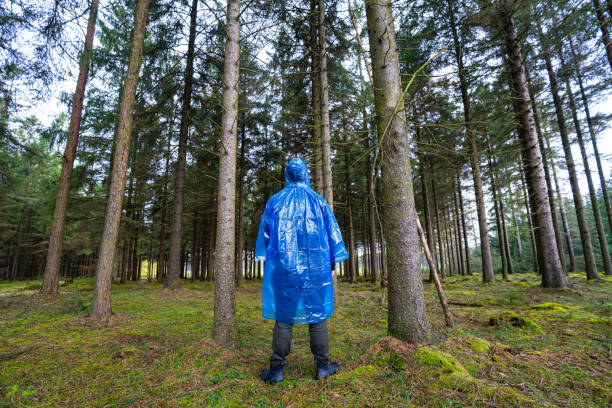 istock Man in blue plastic poncho walking in a forest 2154821405