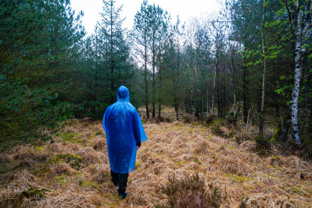 istock Man in blue plastic poncho walking in a forest 2154821425