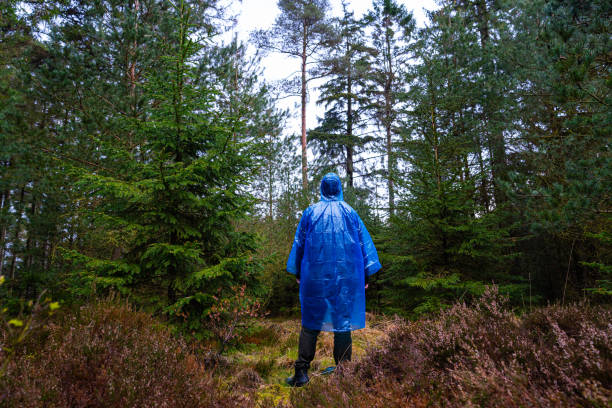 istock Man in blue plastic poncho walking in a forest 2154821435