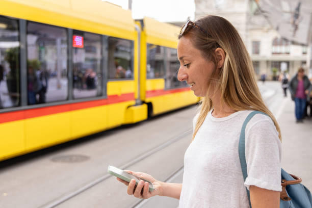 istock Woman Using Smartphone at Tram Station with Yellow Tram 2154824490