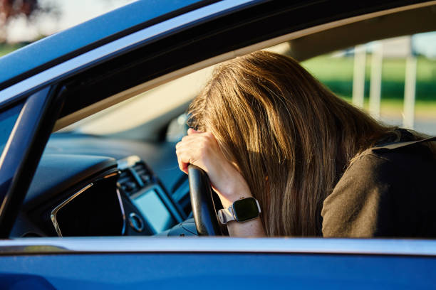 istock Woman is seated inside car with her head resting on steering wheel 2154824626
