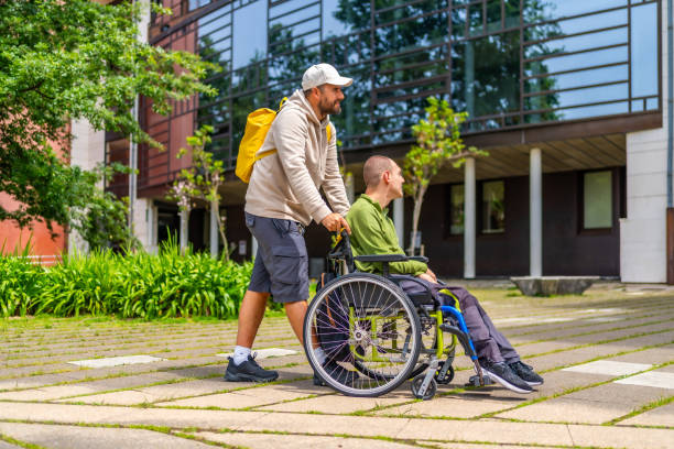 istock Man pushing happy university student in wheelchair along the campus 2154825019