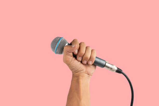 istock Black male hand holding a microphone isolated on pink background 2154828187