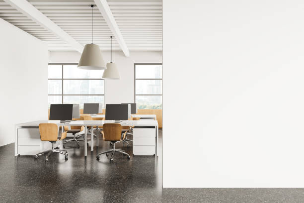 istock Stylish coworking interior with pc computers on desks and window. Mockup wall 2154828637