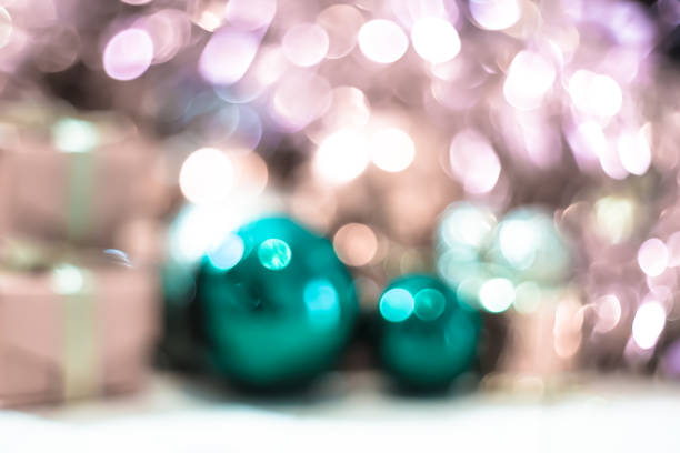 Christmas ornaments ball rainbow colors hanging over red glittering defocused background decorated with garland lights and falling snow with copy space. Banner, website header, poster.