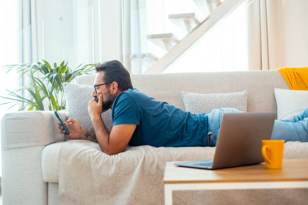 istock One man laying on sofa in chilling relaxation using mobile phone to surf the net or scrolling social media contents. Lazy afternoon people with technology and connection. Enjoying smartphone app male 2154832399
