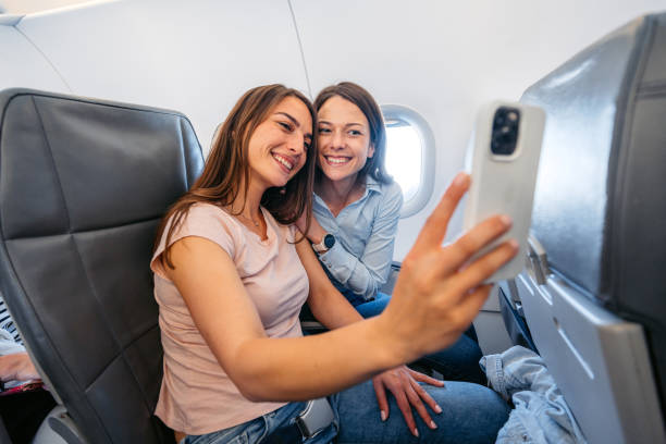 istock Two Young Female Friends Taking Selfies In An Airplane 2154835115