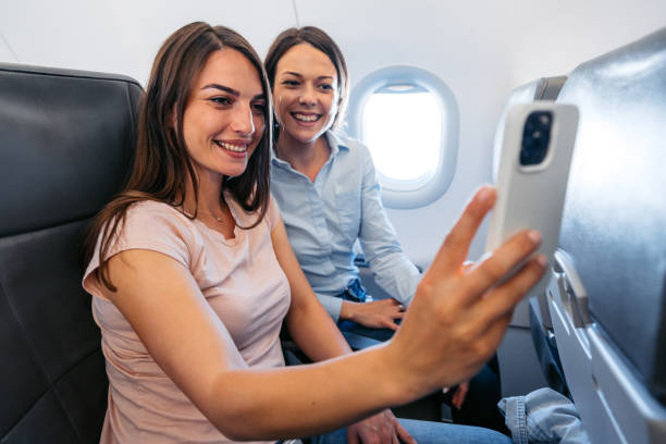 istock Two Young Female Friends Taking Selfies In An Airplane 2154835183